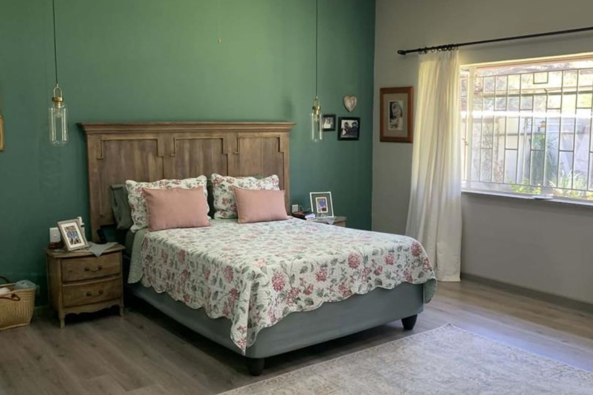 Spacious bedroom featuring wood-look laminate flooring, a green accent wall, recessed ceiling lighting, and a ceiling fan.