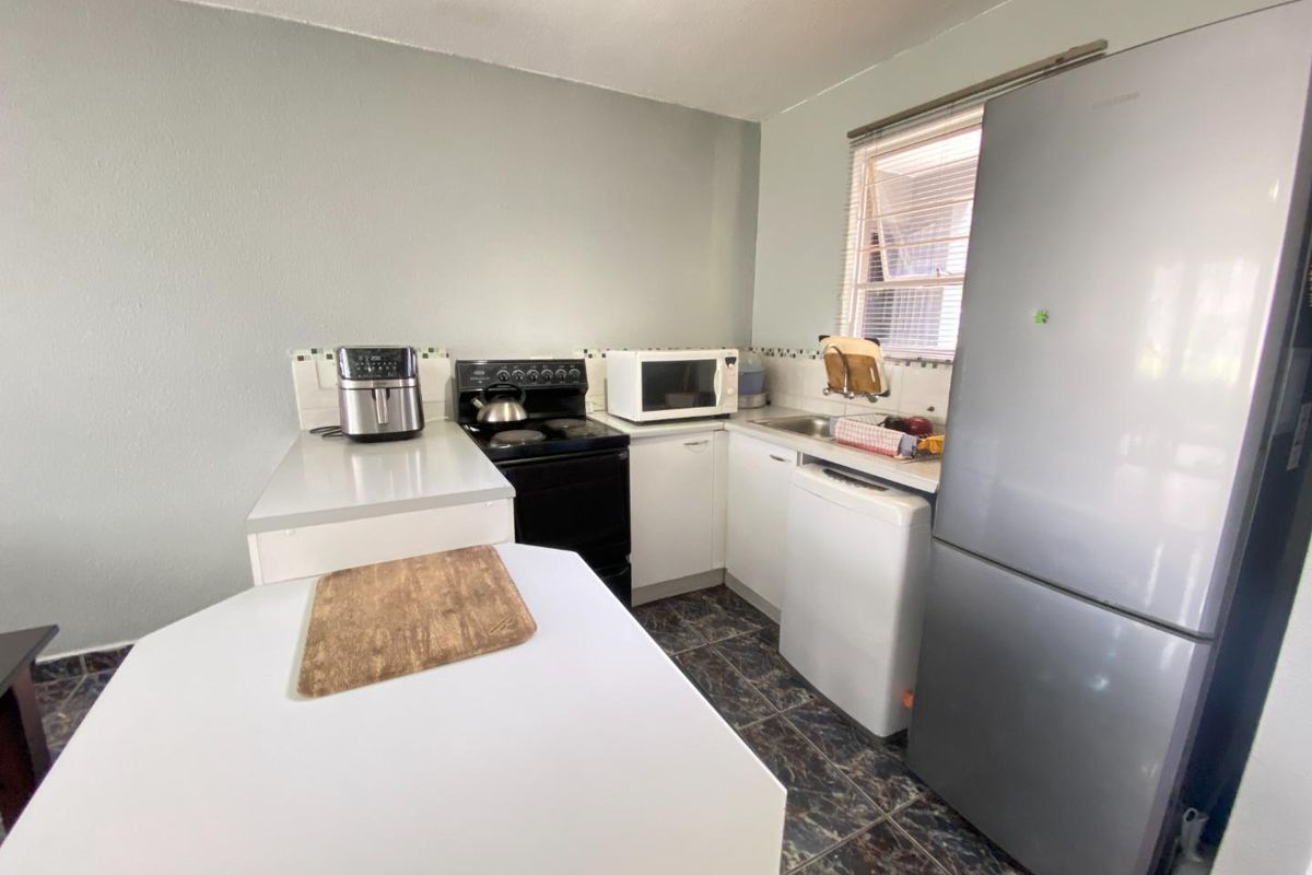 A functional kitchen featuring white cabinetry, tiled flooring, and a built-in stove, offering a practical layout for daily meal preparation.