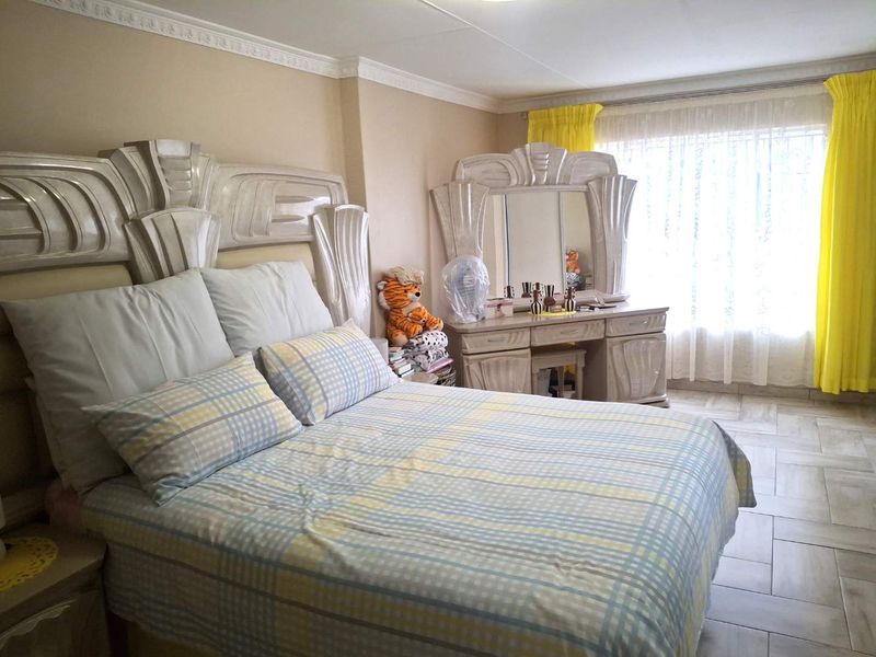 A bedroom featuring tiled flooring and decorative ceiling cornicing, offering a functional space with natural light from the window.