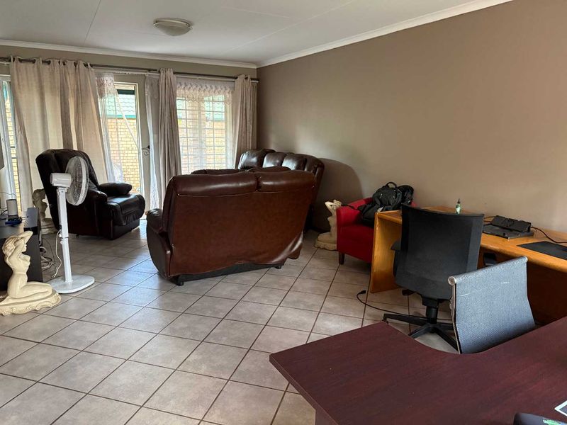 Spacious living area featuring neutral wall tones, tiled flooring, and large sliding glass doors providing access to the exterior.