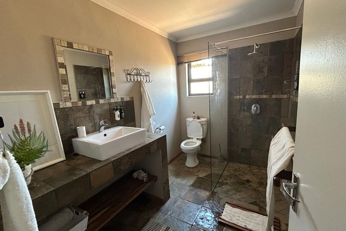 A functional bathroom featuring a walk-in shower with glass screen, a vessel sink on a tiled vanity, and a toilet.