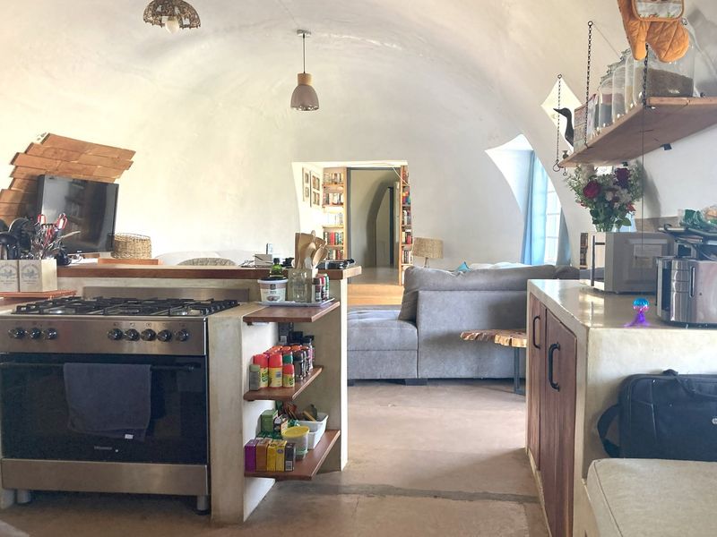 Open-plan living area featuring a unique vaulted ceiling, integrated kitchen with gas stove, and a seamless flow into the adjacent lounge space.