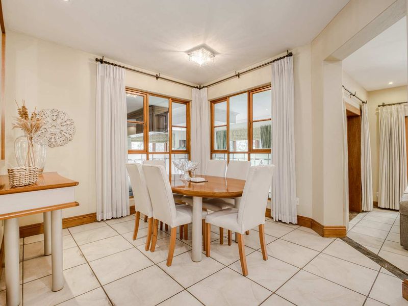A bright dining room featuring tiled flooring, wooden window frames, and neutral wall finishes, providing a clean and functional space for family meals.