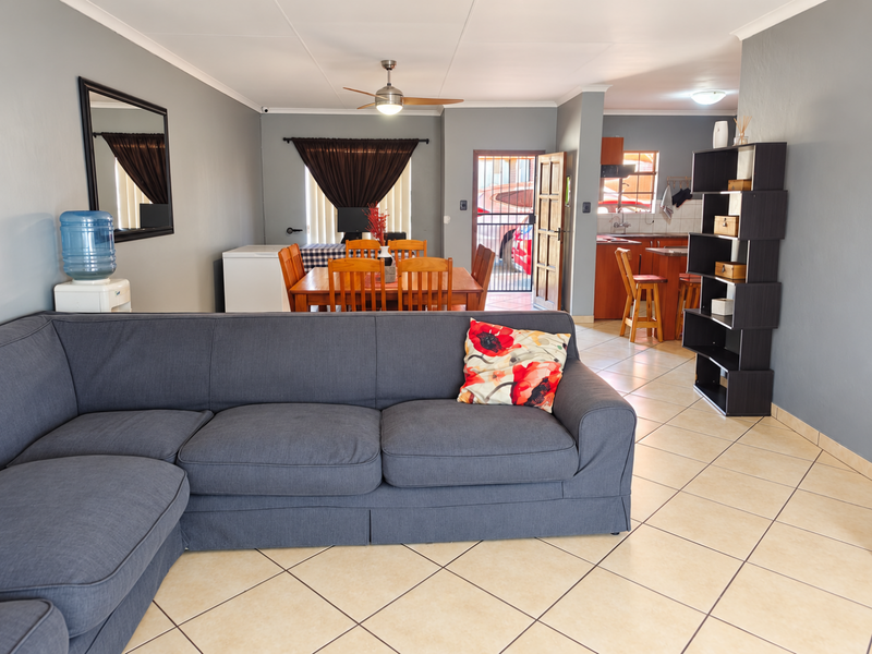 Open-plan living and dining area featuring tiled flooring, a ceiling fan, and a connected kitchen with island seating and direct exterior access.