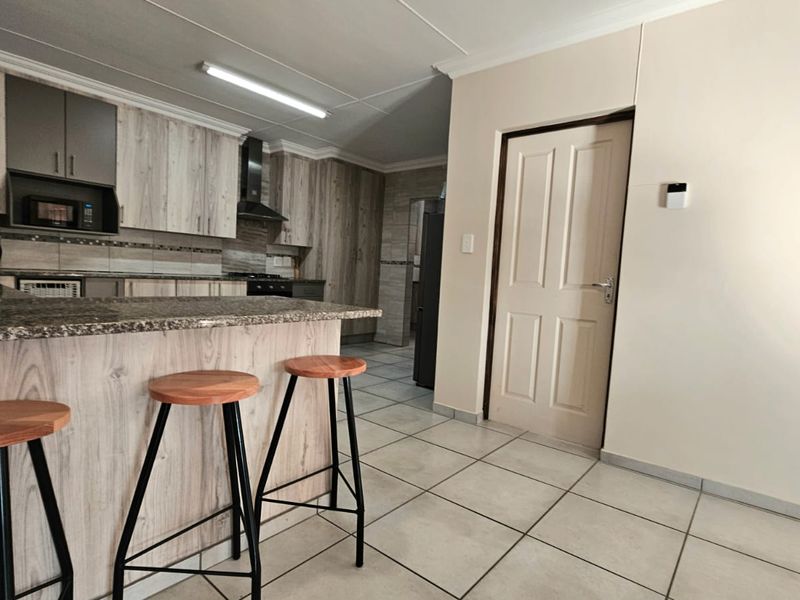 Modern kitchen featuring light wood-grain cabinetry, granite countertops, a breakfast bar, and tiled flooring, offering a functional and well-maintained cooking space.