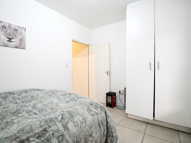 A functional bedroom featuring neutral tiled flooring and a built-in wardrobe, providing essential storage space within the apartment.