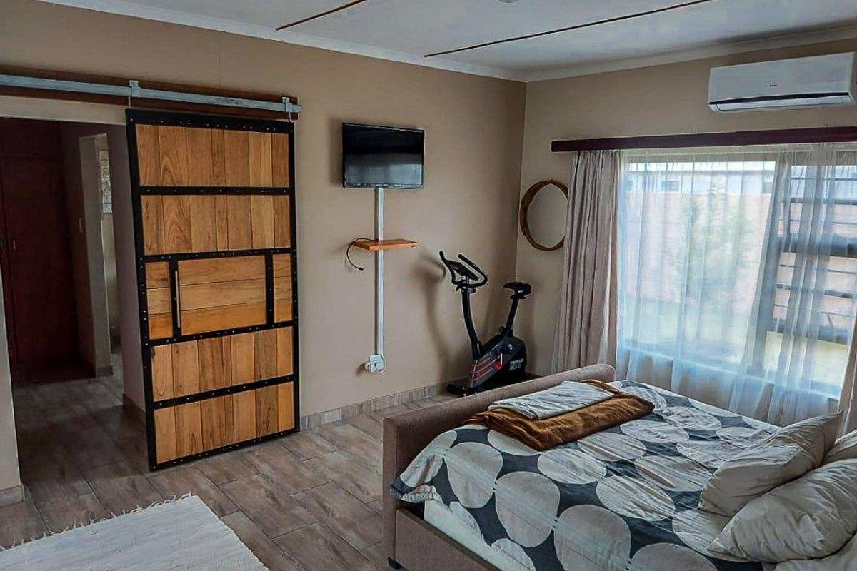 A well-maintained bedroom featuring wood-look tile flooring, a sliding barn-style door, and a wall-mounted air conditioning unit.
