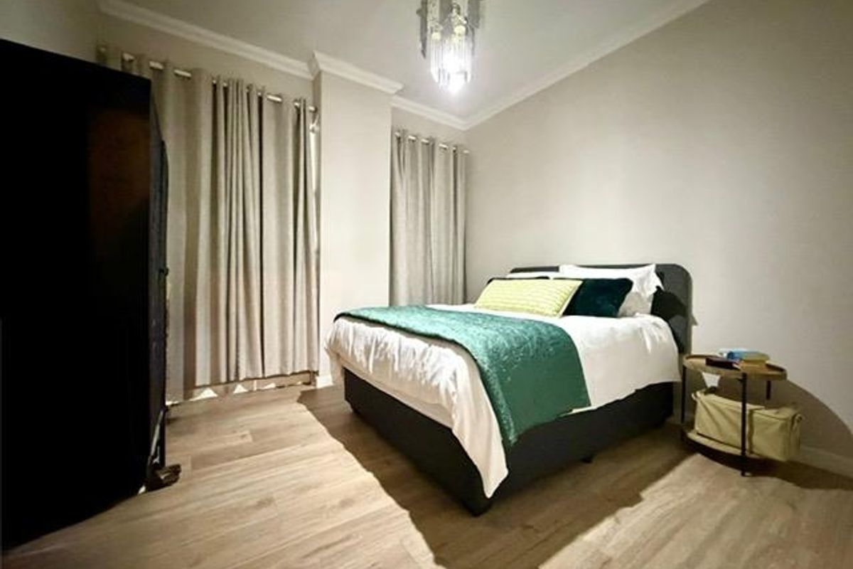 A well-maintained bedroom featuring light-toned laminate flooring, neutral wall finishes, and decorative coving, creating a comfortable and inviting sleeping space.