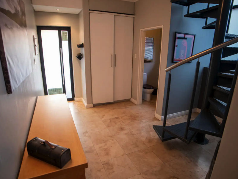 Entrance hall featuring tiled flooring, a modern spiral staircase with metal handrails, and a built-in storage cupboard.