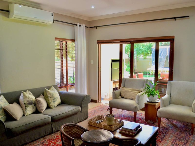 A comfortable living room featuring tiled floors, a wall-mounted air conditioner, and large sliding glass doors that provide direct access to the outdoor patio area.