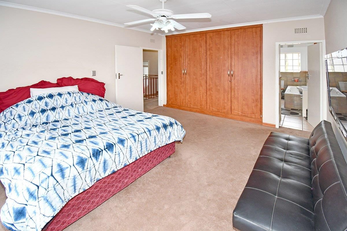 Spacious bedroom featuring built-in wooden cupboards, a ceiling fan, and direct access to an en-suite bathroom.