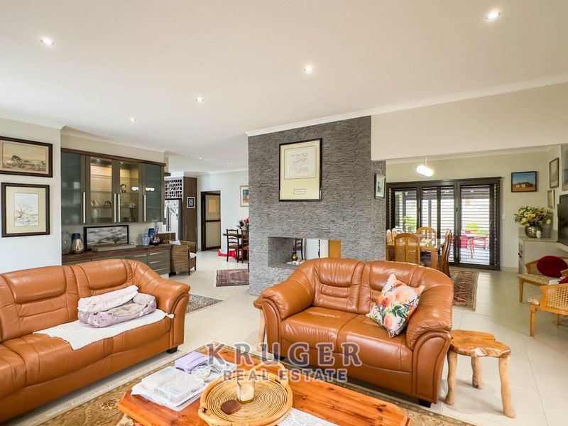 Spacious open-plan living and dining area featuring a central stone-clad fireplace, recessed lighting, and direct access to the outdoor patio through sliding doors.
