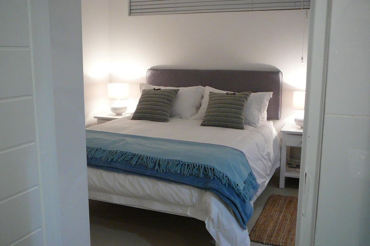 A well-maintained bedroom featuring neutral tiled flooring and horizontal venetian blinds, presented in a clean and tidy condition.