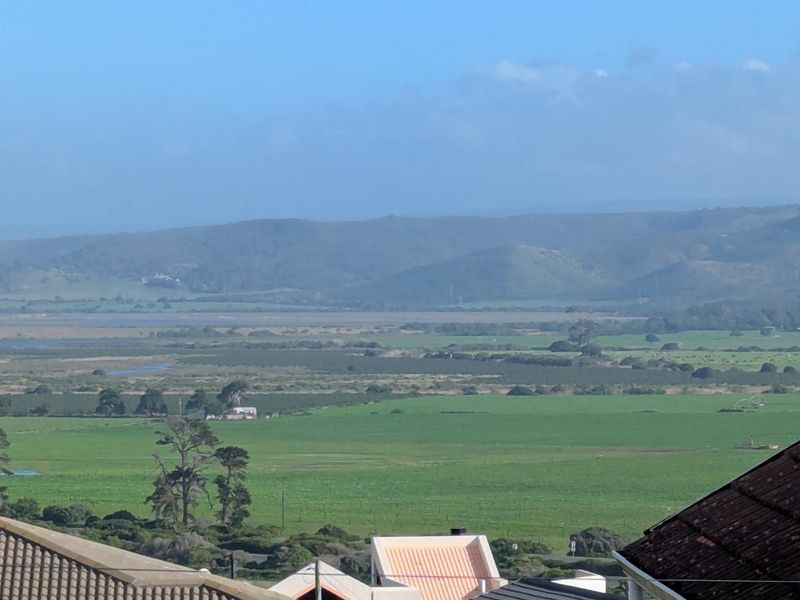 Elevated scenic view overlooking expansive green fields, rural landscape, and distant rolling hills.