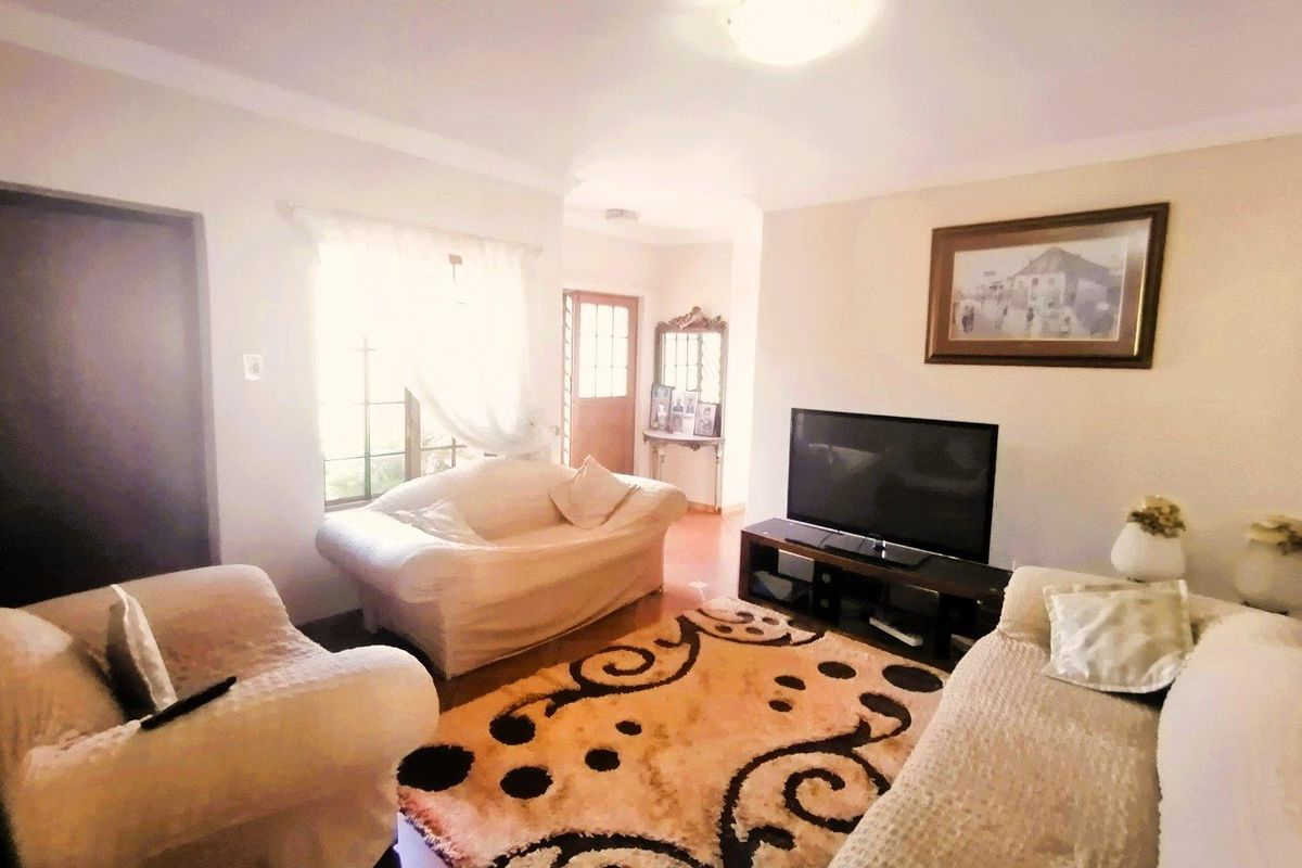 A comfortable living room featuring tiled flooring, neutral wall tones, and natural light from the window, providing a functional and inviting space.