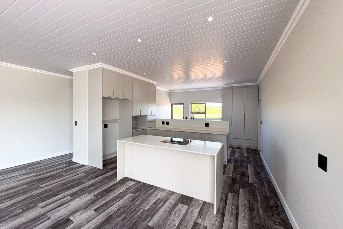 Modern, empty kitchen featuring a central island, sleek built-in cabinetry, recessed lighting, and wood-look laminate flooring in a clean, neutral space.