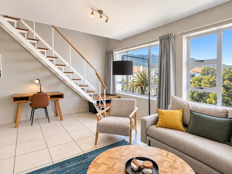 Bright living room featuring tiled flooring, a modern staircase, and large windows offering pleasant neighborhood views.