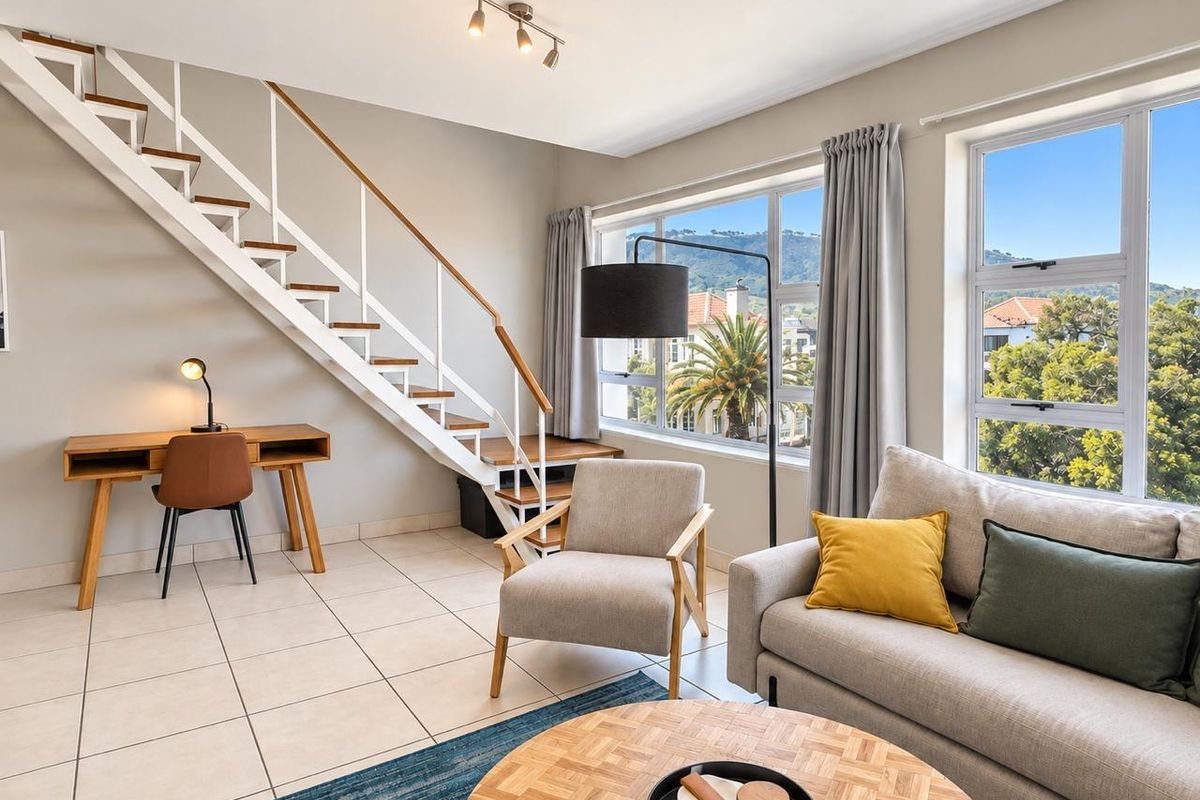 Bright living room featuring tiled flooring, a modern staircase, and large windows offering pleasant neighborhood views.