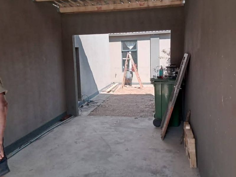 An unfinished garage space featuring exposed timber ceiling joists, corrugated metal roofing, and concrete flooring, providing a blank canvas for completion.