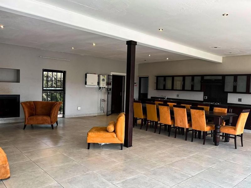 Spacious open-plan living and dining area featuring tiled floors, a built-in fireplace, and a functional kitchen with dark cabinetry.