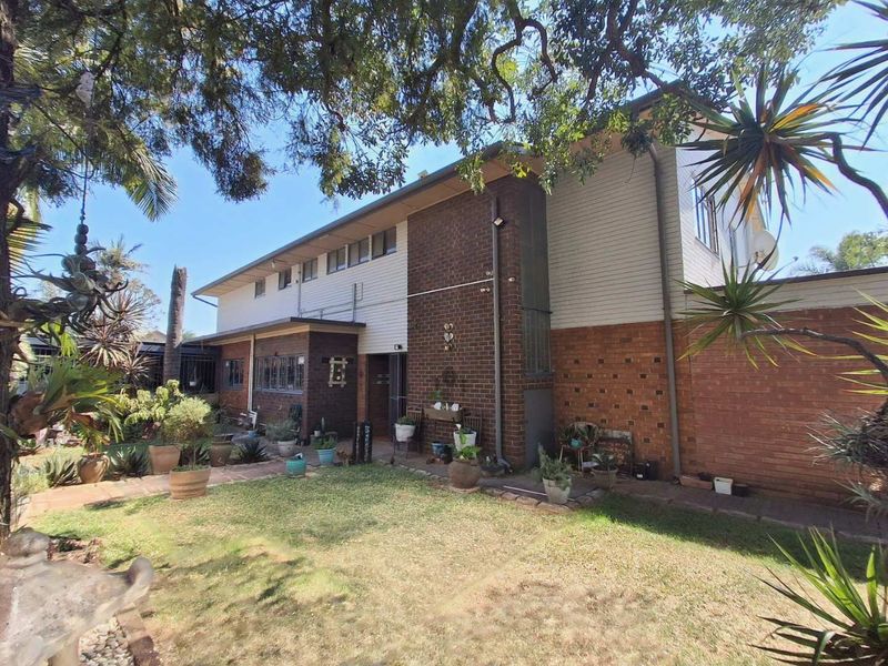 Rear view of the house featuring a combination of brick and weatherboard cladding with a paved walkway leading along the garden.