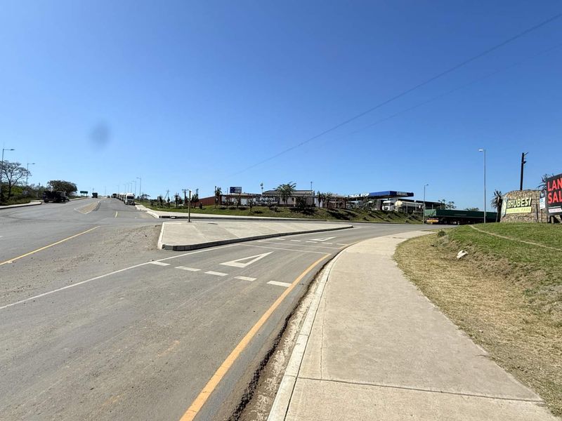 A view of the industrial park entrance from the main road, featuring paved access roads, sidewalks, and prominent signage.