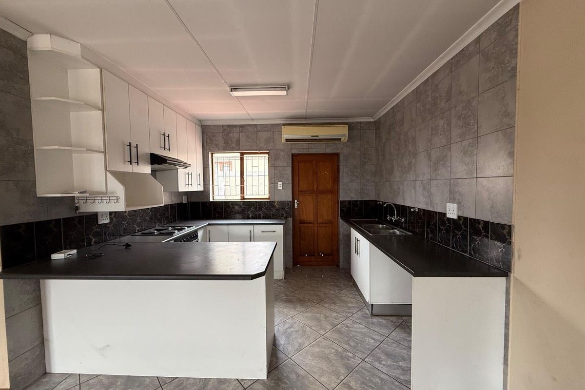 Functional kitchen featuring white cabinetry, dark countertops, tiled splashbacks, tiled flooring, and a built-in stove with extractor fan.