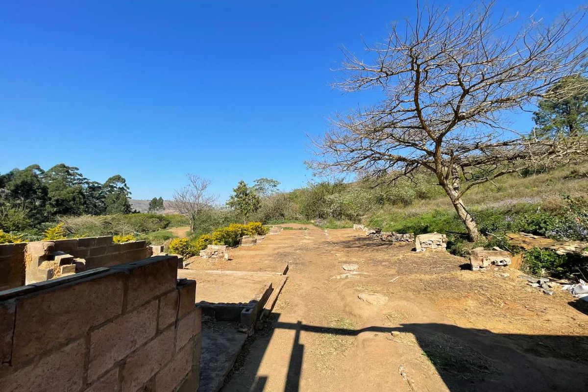 An outdoor area showing the early stages of construction with exposed brick foundations and cleared land, offering potential for development on this small holding.