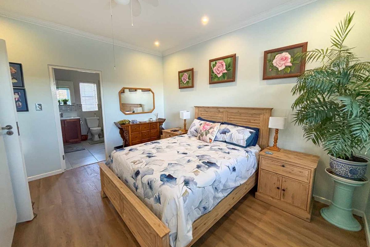 A well-maintained bedroom featuring laminate flooring, recessed lighting, a ceiling fan, and direct access to an en-suite bathroom.