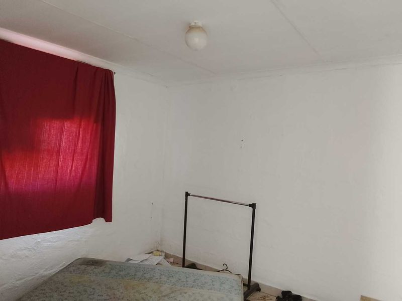 A simple, vacant bedroom featuring plain white walls and a basic ceiling light fixture, offering a blank canvas for renovation.