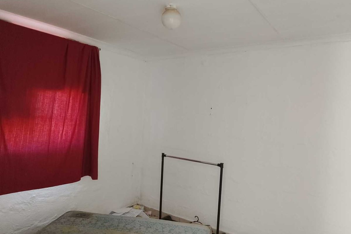 A simple, vacant bedroom featuring plain white walls and a basic ceiling light fixture, offering a blank canvas for renovation.