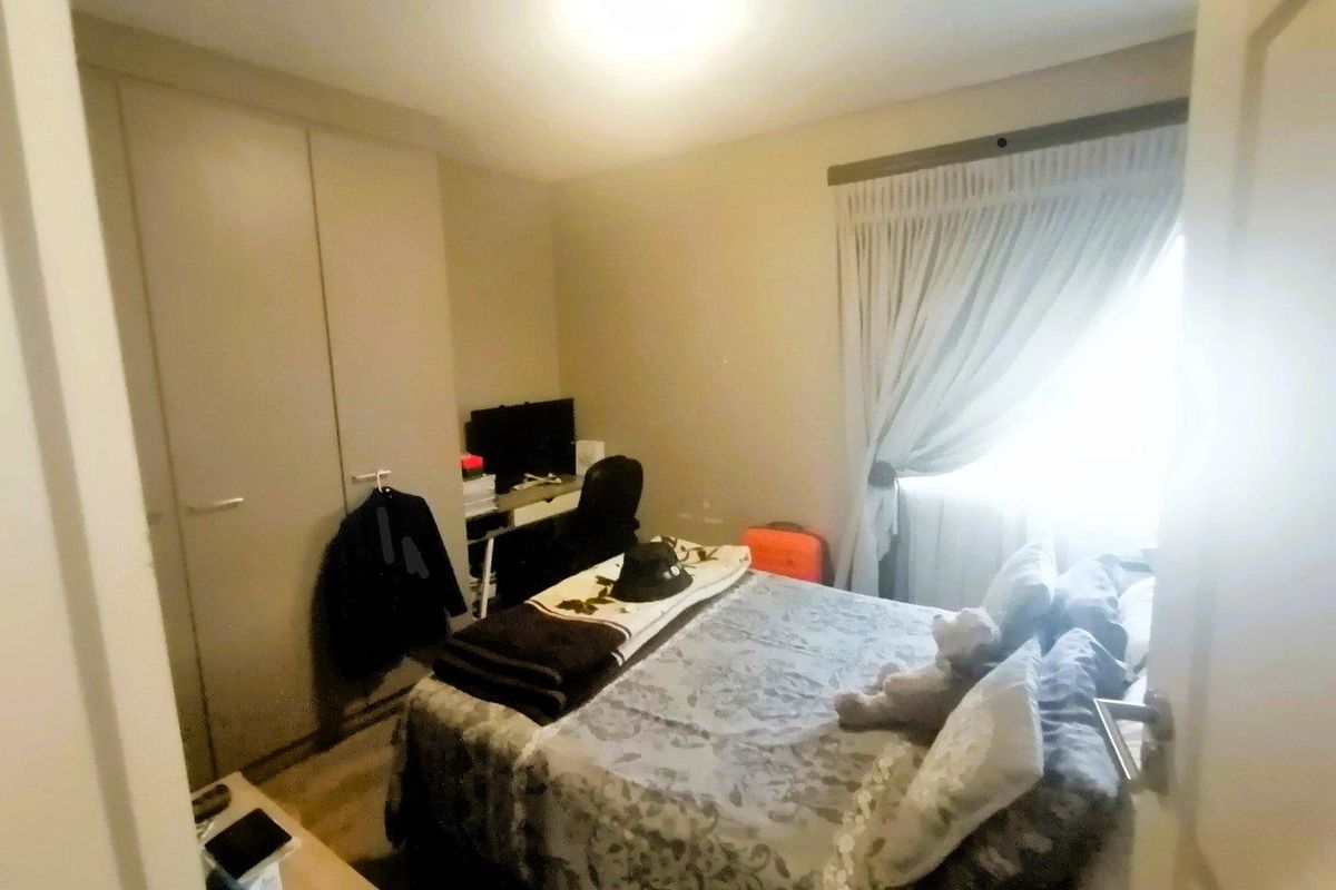 A functional bedroom featuring built-in cupboards and a window with curtain tracks, providing a comfortable and practical living space.