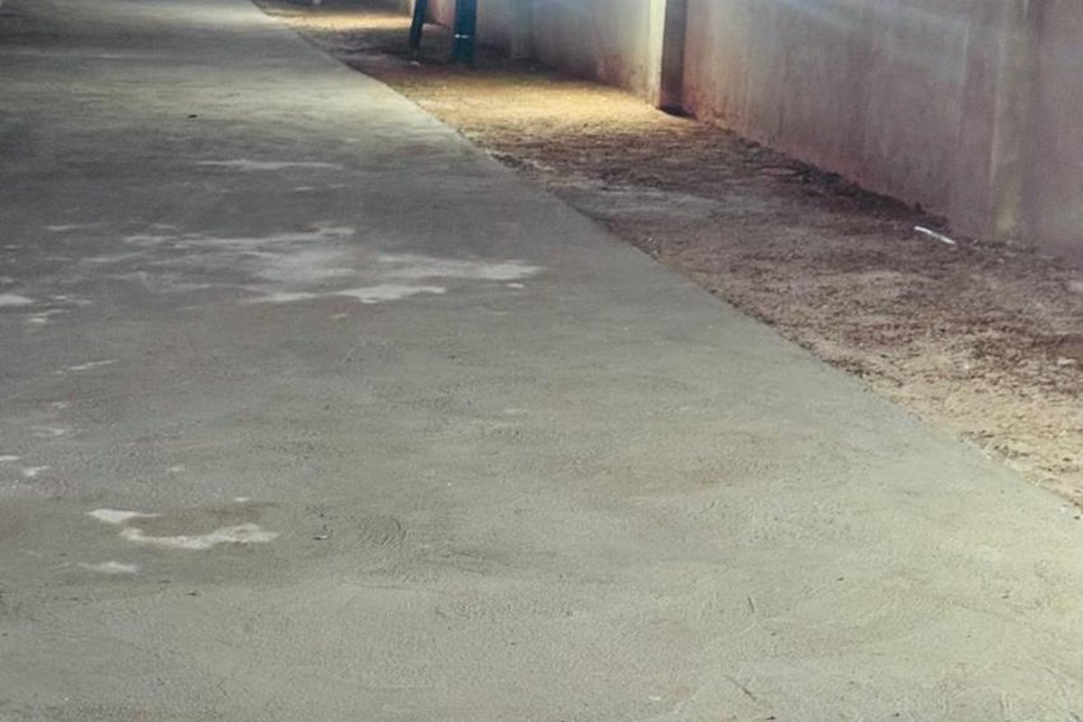 A concrete driveway at dusk featuring perimeter walling and installed exterior lighting fixtures.