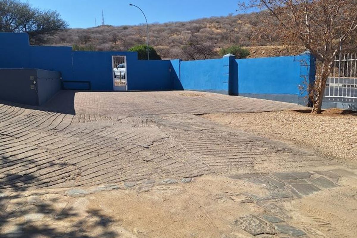 An outdoor paved area featuring a blue perimeter wall, providing a secure and open space suitable for parking or exterior utility use.