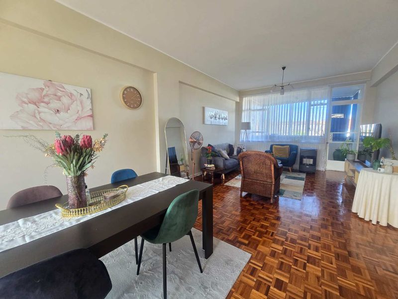 Spacious open-plan living and dining area featuring classic parquet flooring and large windows that provide ample natural light.