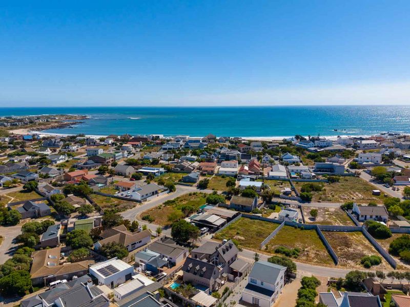 An elevated aerial view of a coastal residential neighborhood, showcasing the proximity to the ocean and surrounding landscape.