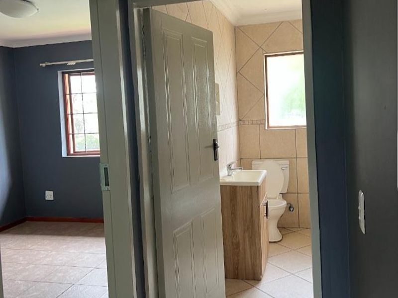 A view from the hallway looking into an adjacent bedroom and a bathroom featuring a vanity and toilet.