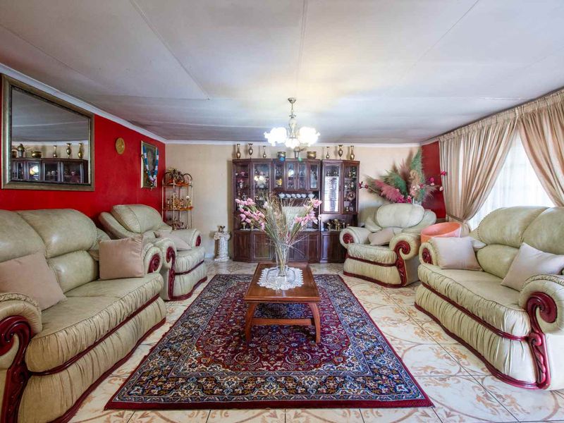 A spacious living room featuring tiled flooring and a coved ceiling, offering a traditional layout ready for modern updates.