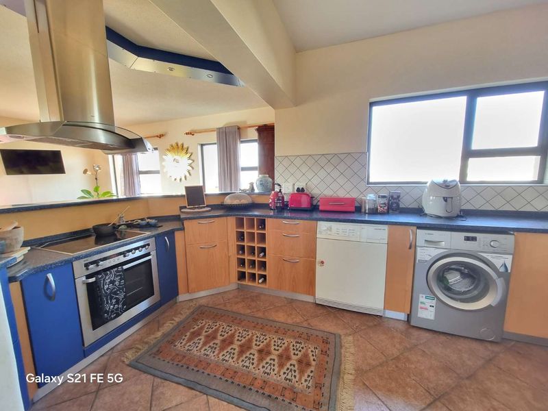 A functional kitchen featuring laminate cabinetry, a built-in oven with extractor fan, tiled backsplash, and tiled flooring, offering a practical layout for daily use.