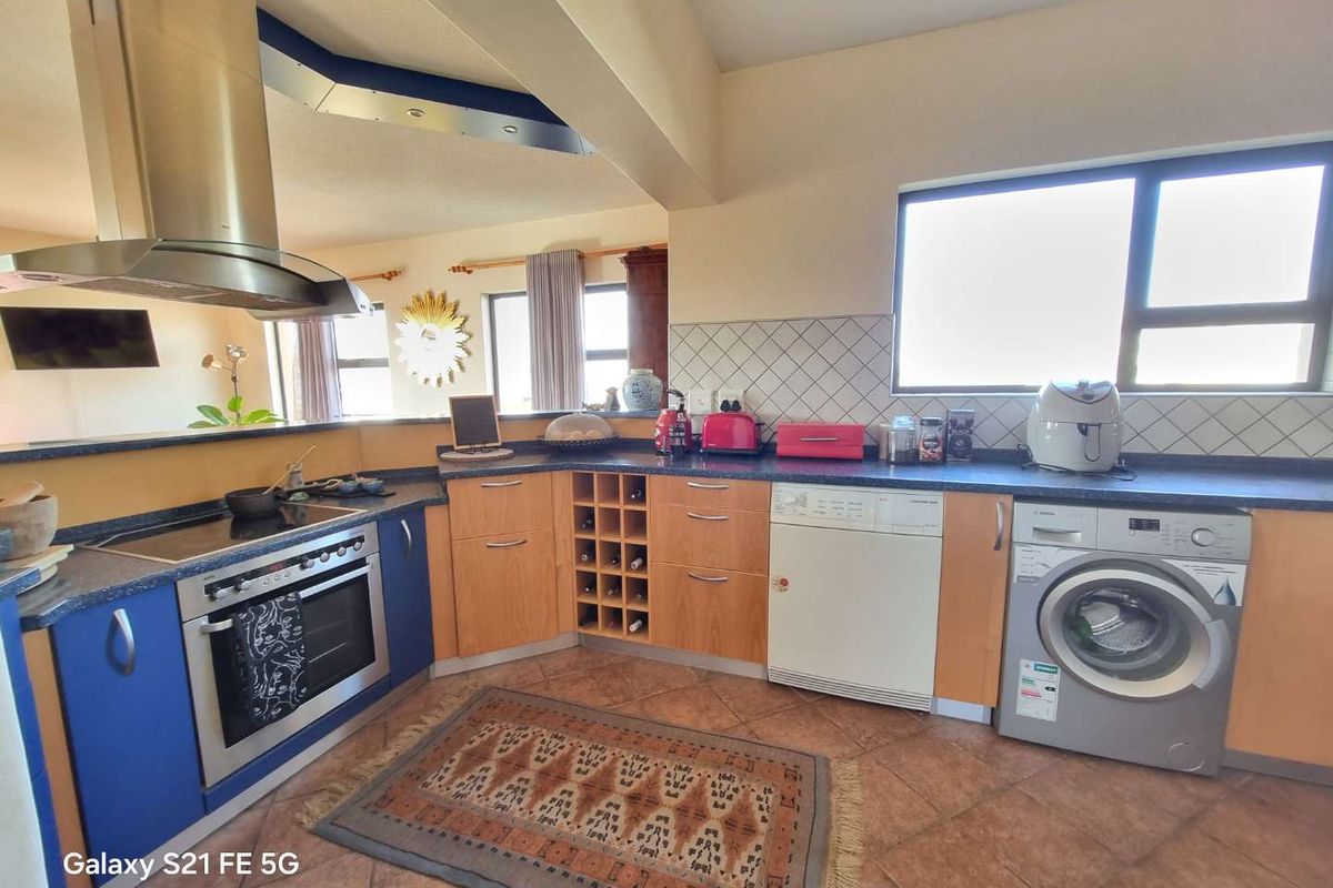A functional kitchen featuring laminate cabinetry, a built-in oven with extractor fan, tiled backsplash, and tiled flooring, offering a practical layout for daily use.