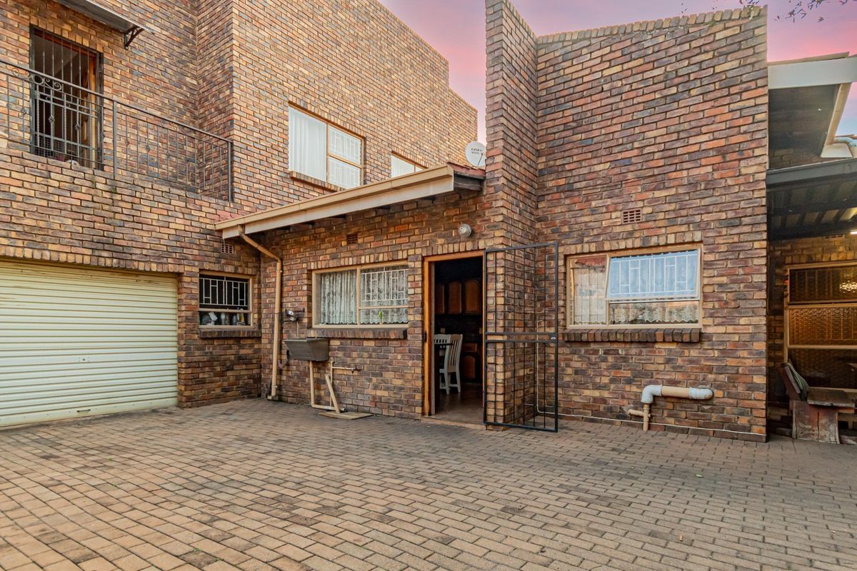 Rear courtyard area featuring face brick construction, paved flooring, a garage entrance, and an external wash basin.