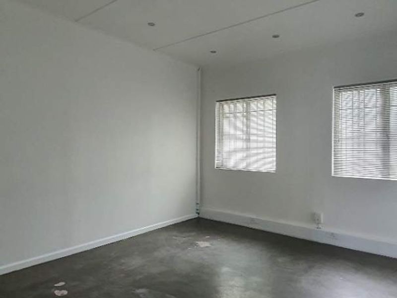 An empty office space featuring polished concrete flooring, recessed ceiling lighting, and windows fitted with venetian blinds.