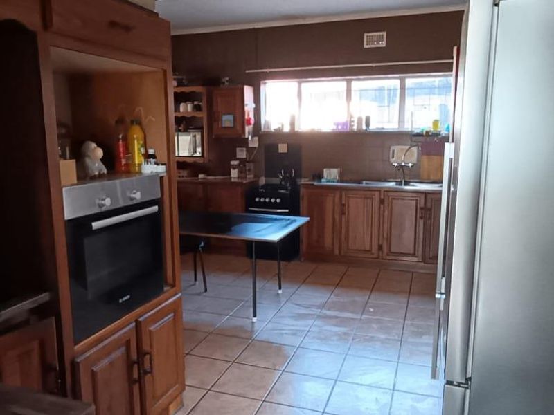 A functional kitchen featuring traditional wooden cabinetry, tiled flooring, and a built-in oven, offering a classic layout with potential for modern updates.