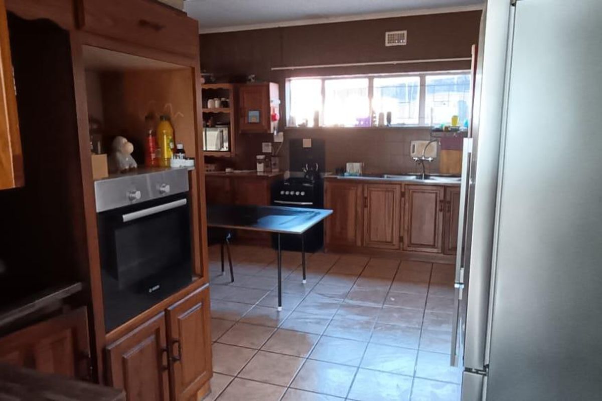 A functional kitchen featuring traditional wooden cabinetry, tiled flooring, and a built-in oven, offering a classic layout with potential for modern updates.