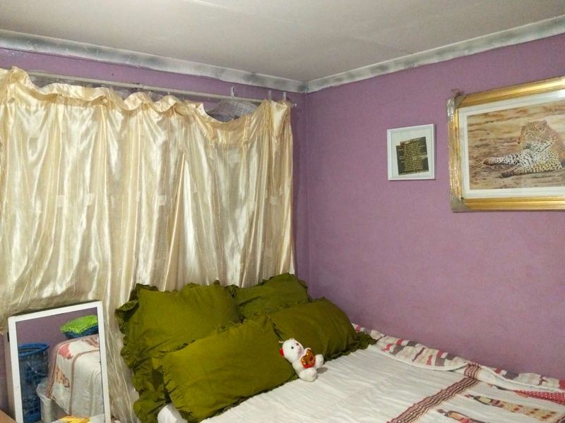 A bedroom featuring purple walls and a curtained window area, requiring cosmetic updates to improve the overall finish and aesthetic appeal.