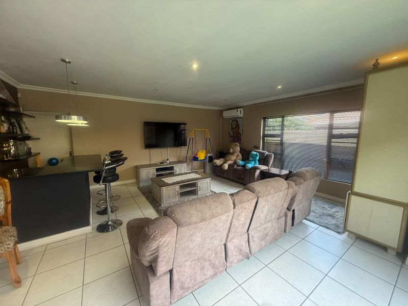 Spacious open-plan living area featuring tiled flooring, a breakfast bar, recessed lighting, and an integrated air conditioning unit.