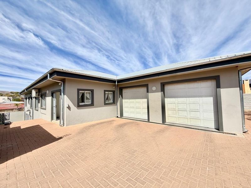 Front exterior view of the property featuring a paved driveway and a double garage with white sectional doors.