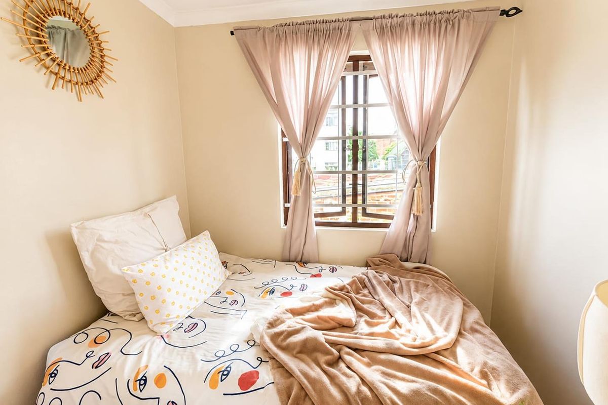 A cozy bedroom featuring a window with fitted security bars and decorative coving, providing a functional and comfortable sleeping space.