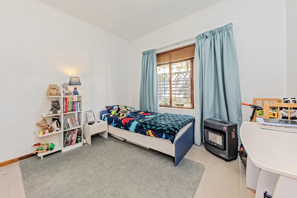 A bedroom featuring tiled flooring, a window with wooden blinds, and neutral wall finishes.