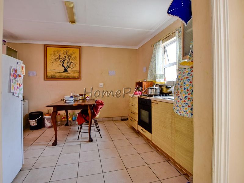 A functional kitchen area featuring built-in cabinetry, an integrated oven and hob, and tiled flooring, requiring cosmetic updates to improve its overall condition.